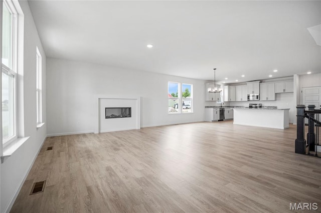 177 Arpent Aly, Saint Charles, MO 63301 - unfurnished living room with a chandelier, light wood-style floors, and recessed lighting