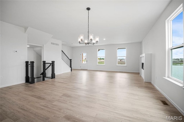 177 Arpent Aly, Saint Charles, MO 63301 - unfurnished living room with light wood-style floors, a chandelier, and stairway