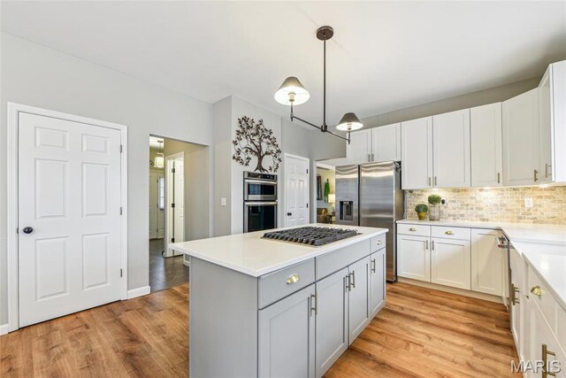 2 Meramec Shores Ct, Ofallon, MO 63366 - kitchen with stainless steel appliances, light wood-type flooring, light countertops, backsplash, and a kitchen island