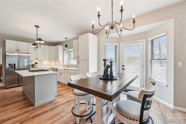 2 Meramec Shores Ct, Ofallon, MO 63366 - kitchen with built in refrigerator, a kitchen island, decorative backsplash, light wood-style flooring, and white cabinets