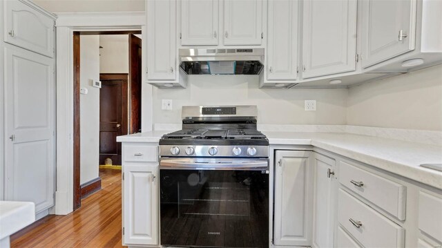 125 W 2nd St, Hermann, MO 65041 - kitchen with stainless steel range with gas cooktop, under cabinet range hood, light countertops, light wood-style flooring, and white cabinets