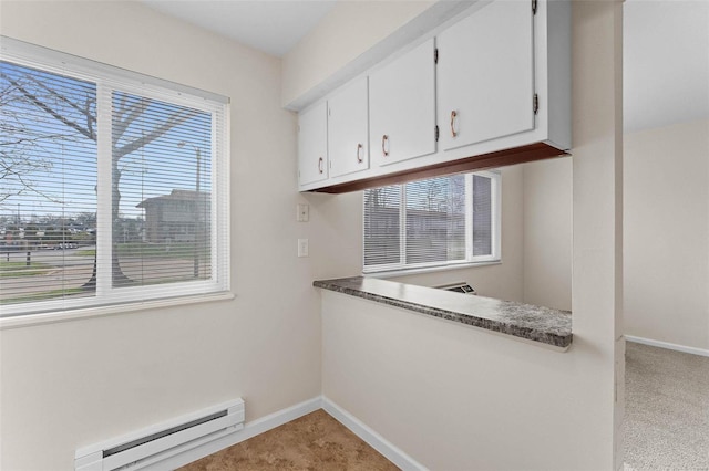 unfurnished dining area with a baseboard heating unit, baseboards, and light colored carpet