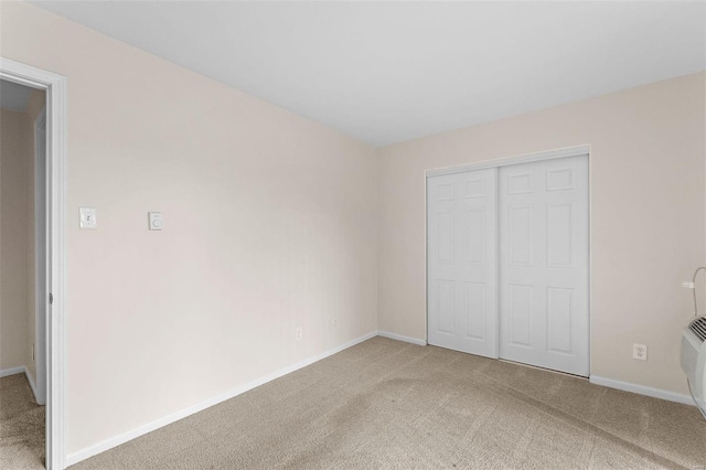 unfurnished bedroom featuring light colored carpet, baseboards, and a closet