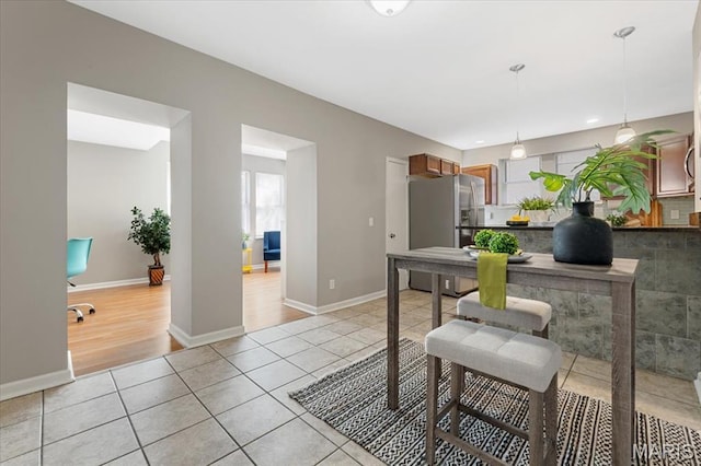 3618 Mcree Ave, Saint Louis, MO 63110 - kitchen featuring stainless steel refrigerator with ice dispenser, light tile patterned floors, hanging light fixtures, baseboards, and dark countertops