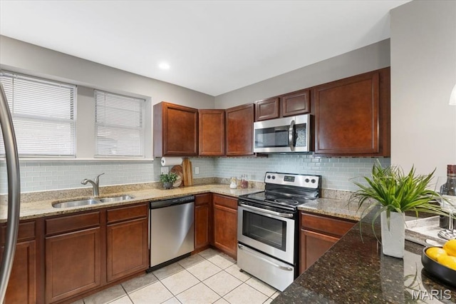 3618 Mcree Ave, Saint Louis, MO 63110 - kitchen featuring appliances with stainless steel finishes, a sink, decorative backsplash, stone countertops, and light tile patterned flooring