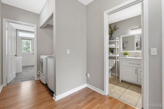 3618 Mcree Ave, Saint Louis, MO 63110 - laundry area with washer and clothes dryer, light wood-style floors, and baseboards