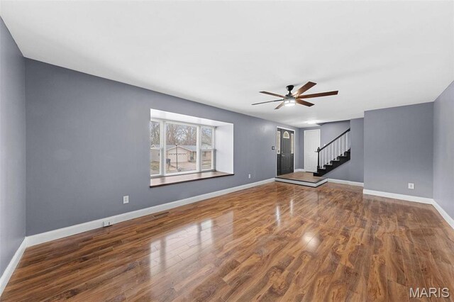 2915 Coram Dr, Saint Louis, MO 63129 - unfurnished living room featuring ceiling fan, baseboards, wood finished floors, and stairway