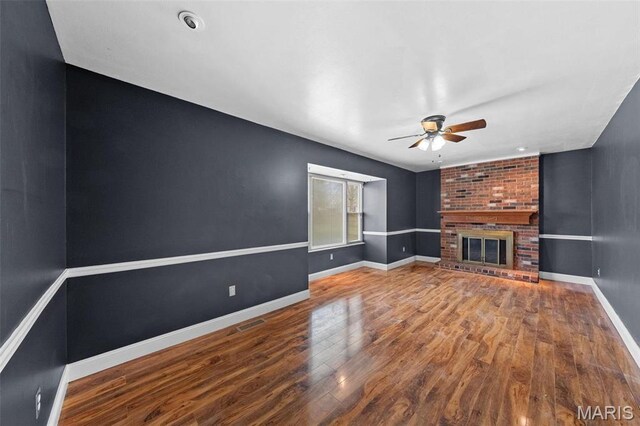 2915 Coram Dr, Saint Louis, MO 63129 - unfurnished living room featuring a ceiling fan, wood finished floors, a brick fireplace, and baseboards
