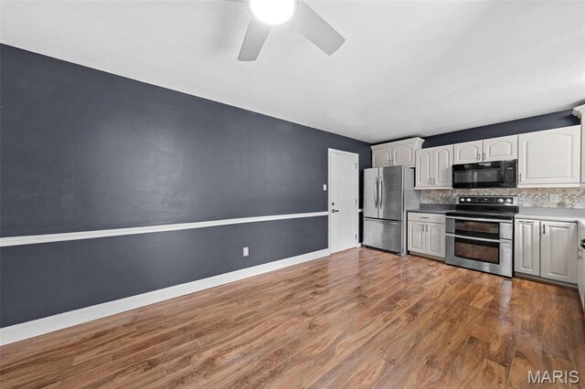 2915 Coram Dr, Saint Louis, MO 63129 - kitchen featuring stainless steel appliances, wood finished floors, a ceiling fan, decorative backsplash, and white cabinets
