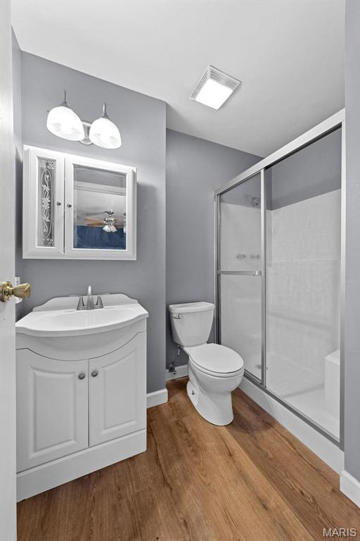 2915 Coram Dr, Saint Louis, MO 63129 - full bathroom featuring toilet, wood finished floors, a stall shower, baseboards, and vanity