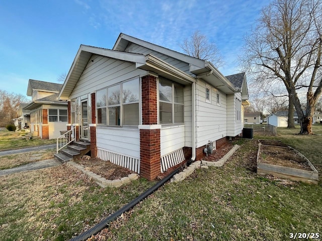 145 S 34th St, Belleville, IL 62226 - view of property exterior featuring entry steps, a vegetable garden, central air condition unit, a lawn, and brick siding