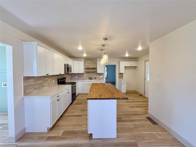 107 S Jackson St, Perryville, MO 63775 - kitchen featuring black electric range, wood counters, stainless steel microwave, decorative backsplash, and a sink