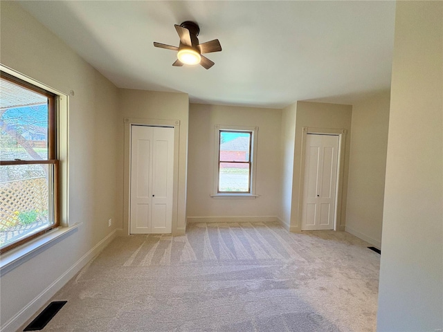 107 S Jackson St, Perryville, MO 63775 - unfurnished bedroom with light colored carpet, two closets, baseboards, and ceiling fan