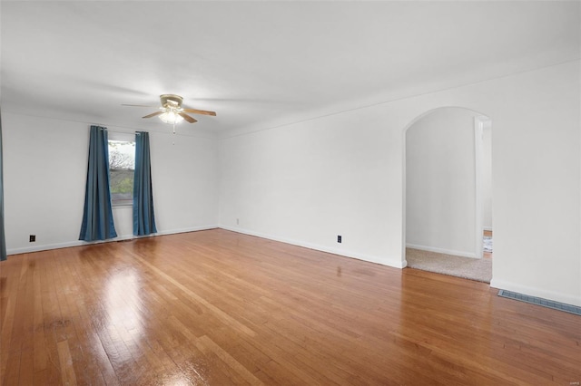 1163 Peace Valley Ln, Hermann, MO 65041 - empty room featuring ceiling fan, arched walkways, hardwood / wood-style floors, and baseboards