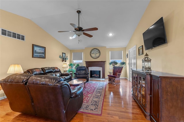 living room featuring lofted ceiling, a ceiling fan, light wood-style flooring, a fireplace, and baseboards