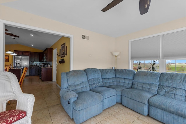 living area featuring a ceiling fan, light tile patterned flooring, and vaulted ceiling