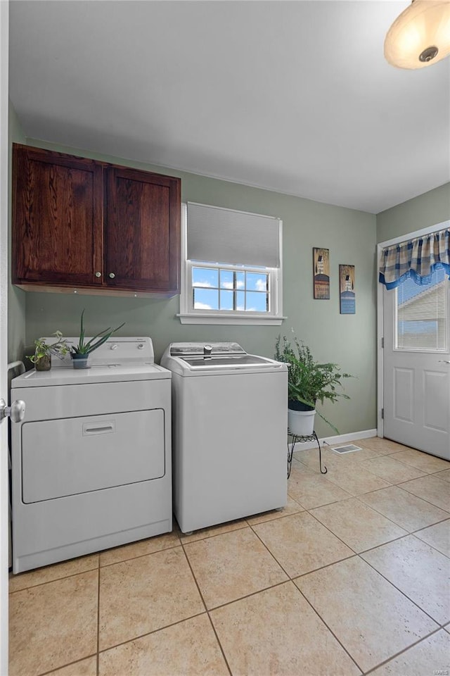 washroom featuring independent washer and dryer, cabinet space, plenty of natural light, and light tile patterned floors