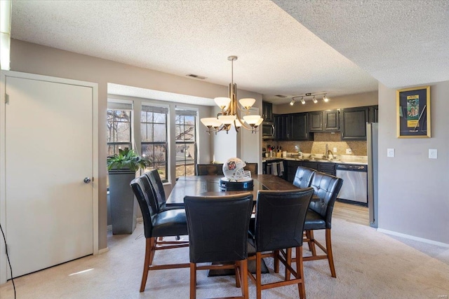 dining area with a chandelier, a textured ceiling, light carpet, and baseboards