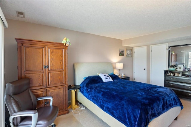 bedroom featuring light carpet and a textured ceiling