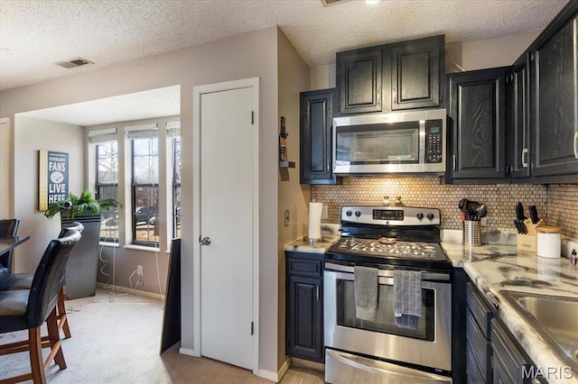 92 Waters Edge Ct Unit 15-2B, Four Seasons, MO 65049 - kitchen with stainless steel appliances, tasteful backsplash, dark cabinetry, light colored carpet, and light countertops