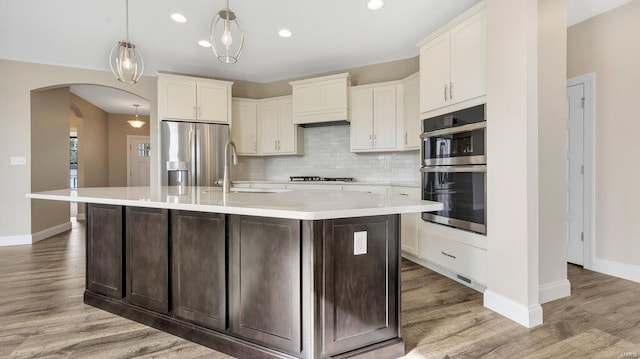 149 Haven Ridge Ct, Dardenne Prairie, MO 63368 - kitchen with a sink, stainless steel appliances, arched walkways, light countertops, and tasteful backsplash