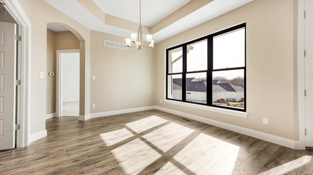 149 Haven Ridge Ct, Dardenne Prairie, MO 63368 - unfurnished room with arched walkways, wood finished floors, a chandelier, baseboards, and a raised ceiling