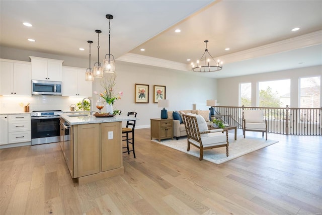 192 Santa Elena Dr, Wentzville, MO 63385 - kitchen featuring stainless steel appliances, a sink, crown molding, an island with sink, and light wood finished floors