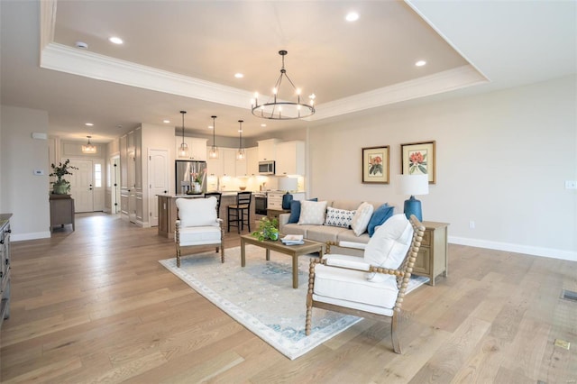 192 Santa Elena Dr, Wentzville, MO 63385 - living room featuring a chandelier, a raised ceiling, ornamental molding, light wood-style floors, and baseboards