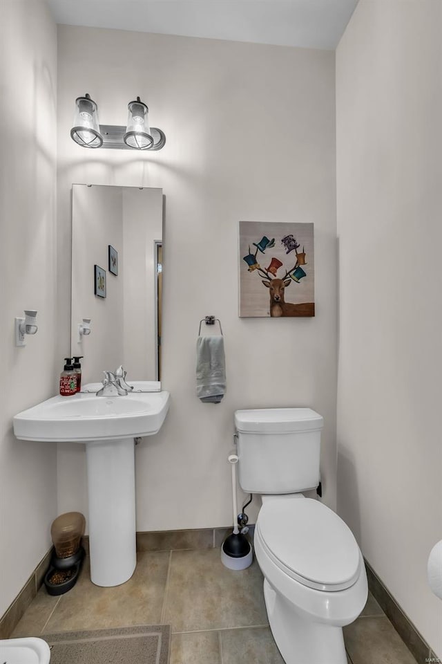 half bathroom with toilet, baseboards, and tile patterned flooring