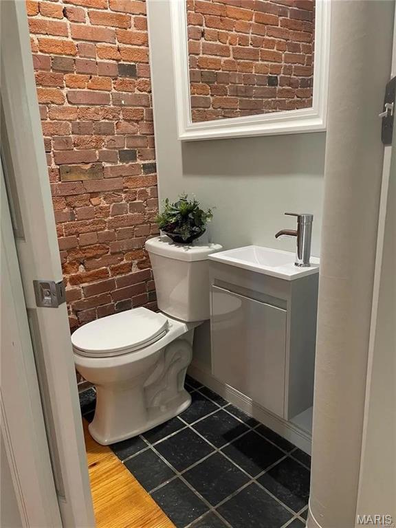 1906 Lasalle St, Saint Louis, MO 63104 - half bathroom with brick wall, toilet, vanity, and tile patterned flooring