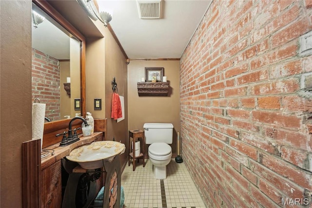 1906 Lasalle St, Saint Louis, MO 63104 - bathroom featuring brick wall, toilet, crown molding, a sink, and tile patterned flooring