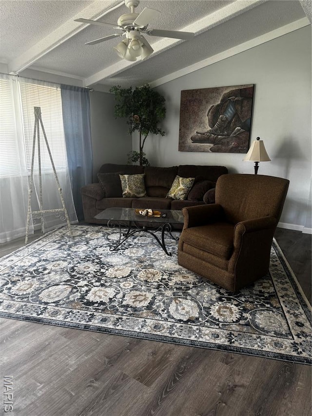 living area featuring a textured ceiling, wood finished floors, ceiling fan, beam ceiling, and baseboards