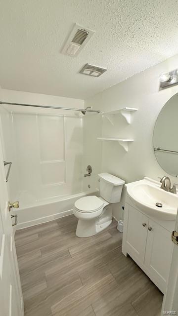 full bathroom featuring toilet, vanity, a textured ceiling, shower / bath combination, and wood finished floors