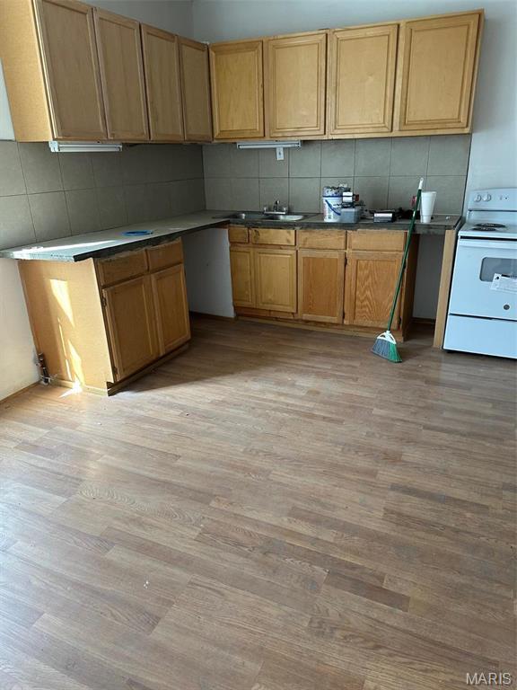 2643 Gravois Ave, Saint Louis, MO 63118 - kitchen with white electric range, light wood-type flooring, and decorative backsplash