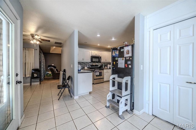 735 Dale Ln, Richland, MO 65556 - kitchen featuring stainless steel range oven, black microwave, light tile patterned floors, dark countertops, and a ceiling fan