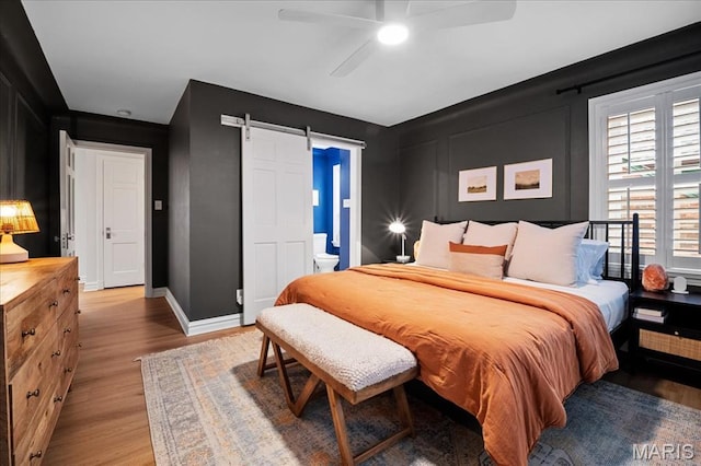 7334 Chamberlain Ave, Saint Louis, MO 63130 - bedroom with light wood-style floors, a barn door, baseboards, and a ceiling fan