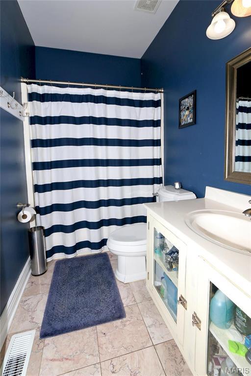 589 Wetherby Terrace Dr, Ballwin, MO 63021 - bathroom with marble look tiles, toilet, vanity, and a shower with shower curtain