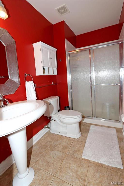 589 Wetherby Terrace Dr, Ballwin, MO 63021 - bathroom featuring toilet, tile patterned floors, and a stall shower
