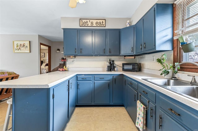 9449 E Lake View Dr, Bonne Terre, MO 63628 - kitchen with a peninsula, blue cabinets, black microwave, a sink, and light countertops