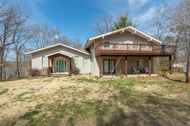 back of property with a lawn, a wooden deck, and a patio area