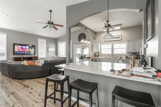 kitchen with ceiling fan, a peninsula, stainless steel appliances, vaulted ceiling, and a sink