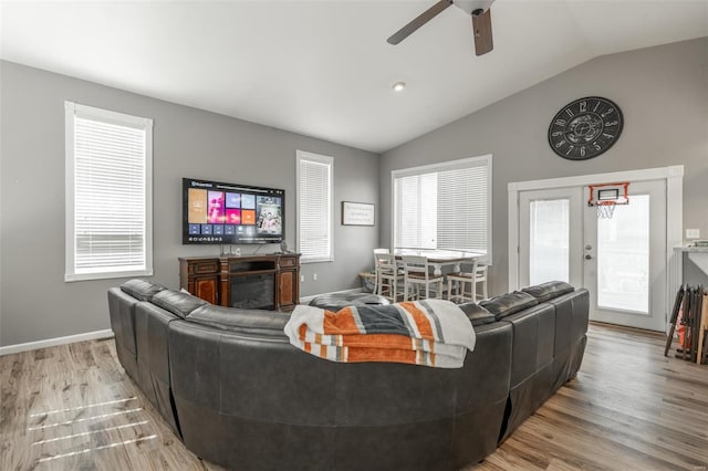 living area with lofted ceiling, ceiling fan, healthy amount of natural light, wood finished floors, and french doors