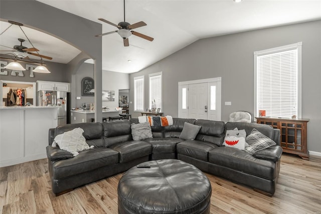 living area featuring ceiling fan, lofted ceiling, light wood-style flooring, and arched walkways
