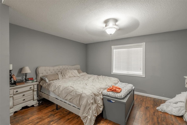 bedroom featuring dark wood finished floors, a textured ceiling, and baseboards