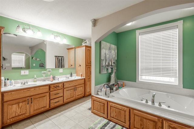 bathroom featuring a tub with jets, tile patterned floors, double vanity, and plenty of natural light