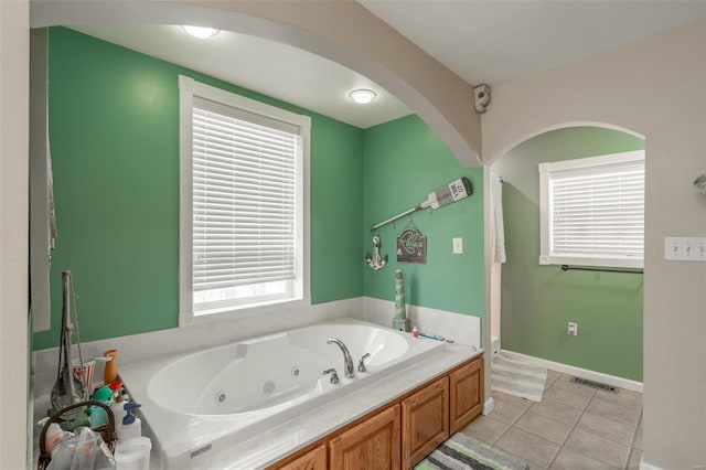 bathroom featuring a tub with jets, tile patterned floors, and baseboards