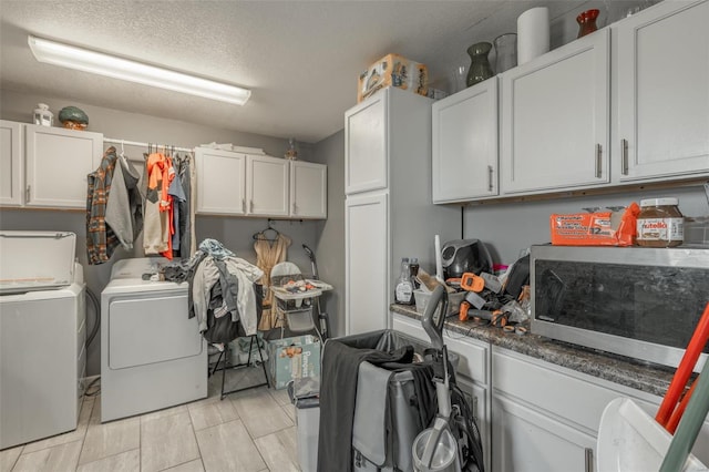 laundry room with washing machine and clothes dryer, cabinet space, and a textured ceiling