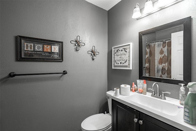 bathroom with toilet, vanity, and curtained shower