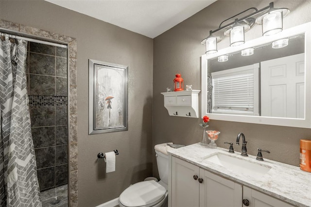 bathroom featuring tiled shower, toilet, vanity, and baseboards