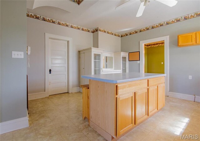 708 E Fillmore St E, Fillmore, IL 62032 - kitchen with light countertops, ceiling fan, baseboards, a kitchen island, and light brown cabinets